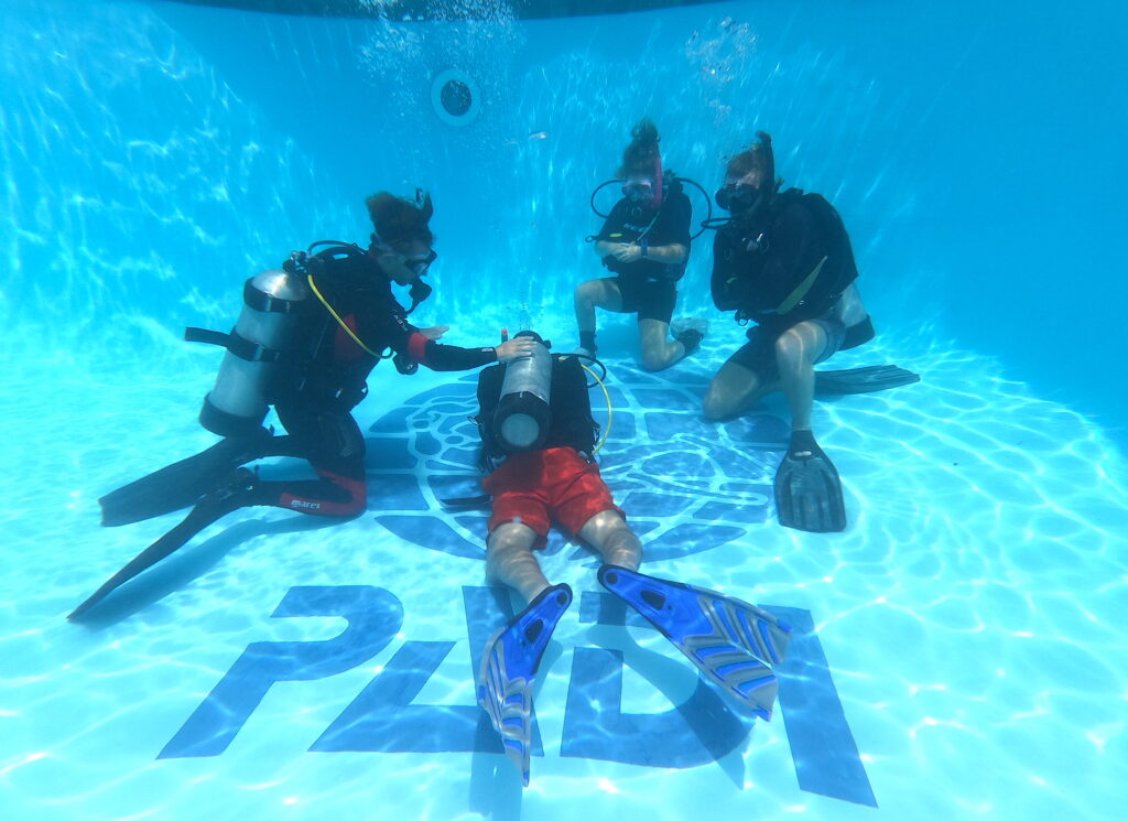PADI IDC Candidates practicing confined water loose cylinder band n the pool